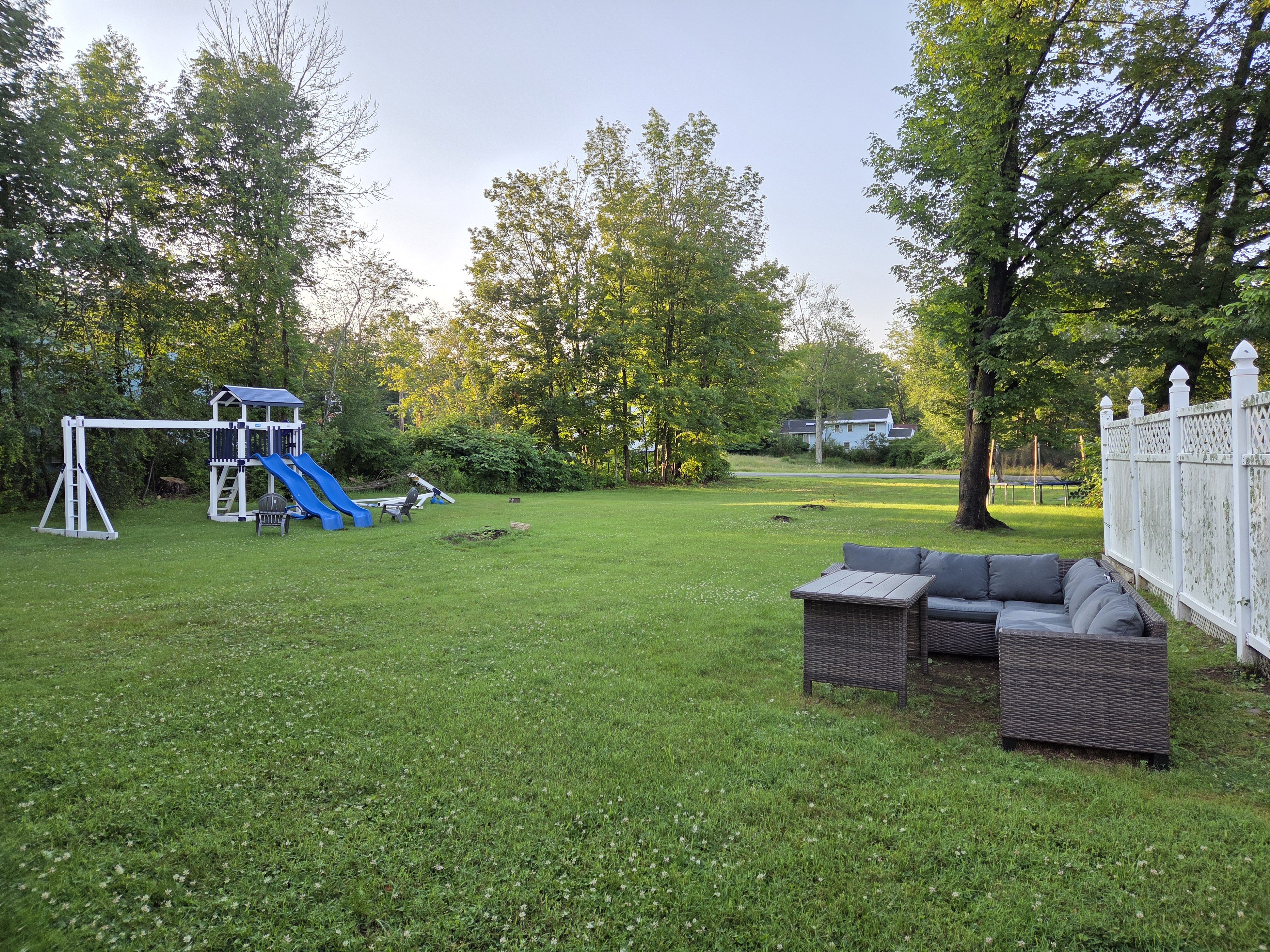 Expansive private fenced backyard lawn with swing set and patio lounge